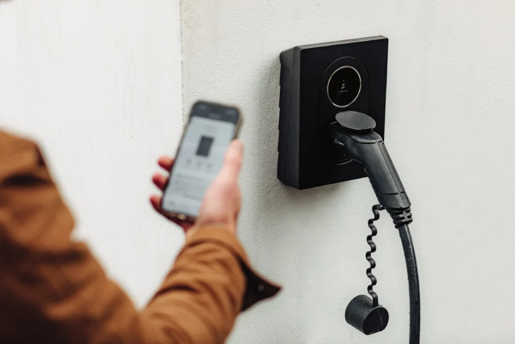 Zaptec go 2 laadstation aan de muur met persoon die app gebruikt
